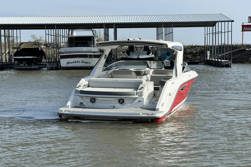 Slide: The Image of 2021 Sea Ray 310 SLX boat docked on calm water near covered marina. - 6
