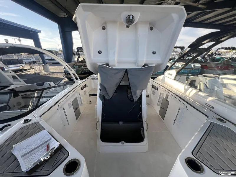 Slide: The Image of 2024 Yamaha Boats 222 FSH Sport interior with open storage compartment, docked in a marina. - 11