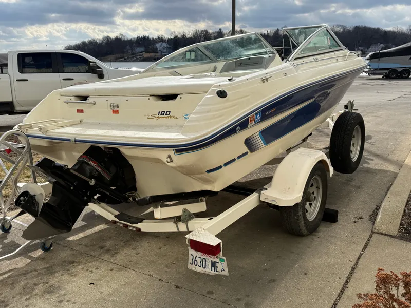 Slide: The Image of 1995 Sea Ray 180 BR boat on trailer, parked outdoors, with cloudy sky background. - 3