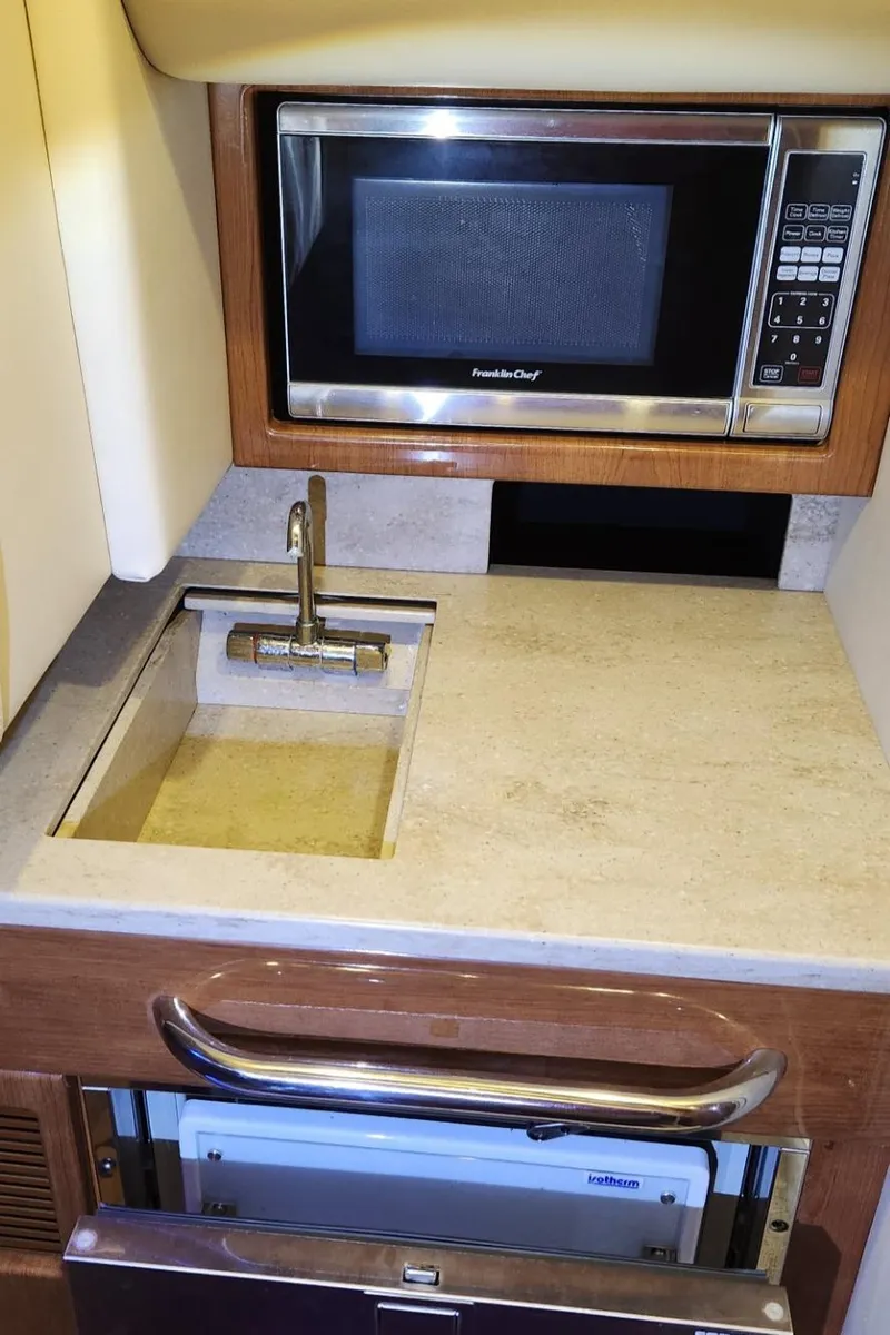 Slide: The Image of Compact kitchenette in a 2015 Formula 350 CBR boat with microwave, sink, and storage. - 48