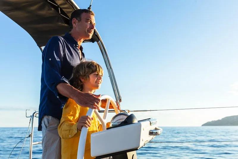 Slide: The Image of Father and child sailing on a 2024 Dufour 530 yacht, enjoying a sunny day at sea. - 3