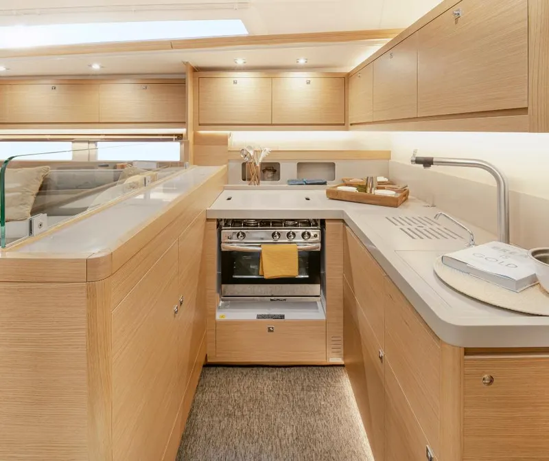 Slide: The Image of 2024 Dufour 530 yacht kitchen interior with modern appliances and wooden cabinetry. - 6