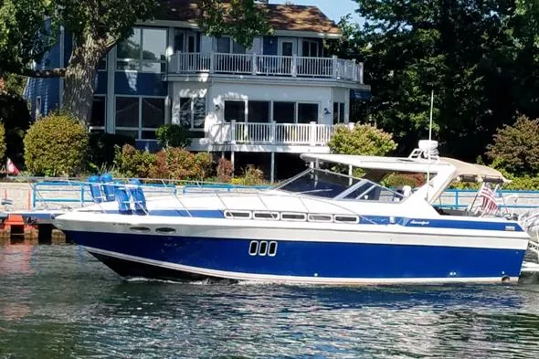 Slide: The Image of 1988 Chris-Craft 412 boat cruising near a waterfront house. - 8