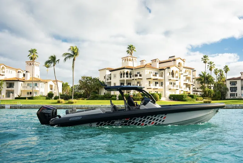 Slide: The Image of 2024 Skipper-BSK 38 boat cruising near luxury waterfront homes. - 2