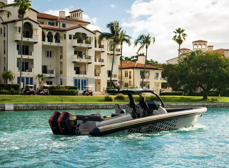 Slide: The Image of 2024 Skipper-BSK 38 boat cruising near luxury waterfront apartments. - 24