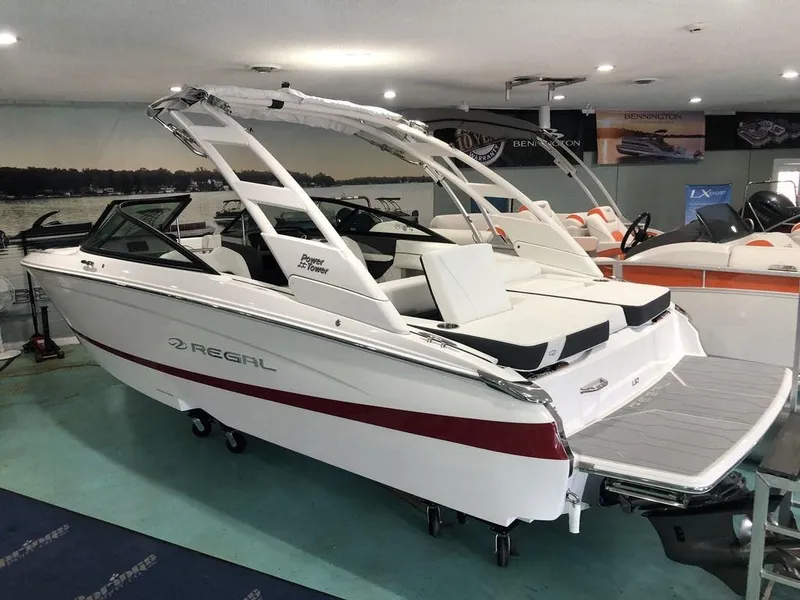 The Image of 2024 Regal LS2 boat in showroom, white with red stripe, sleek design, modern features. - 1