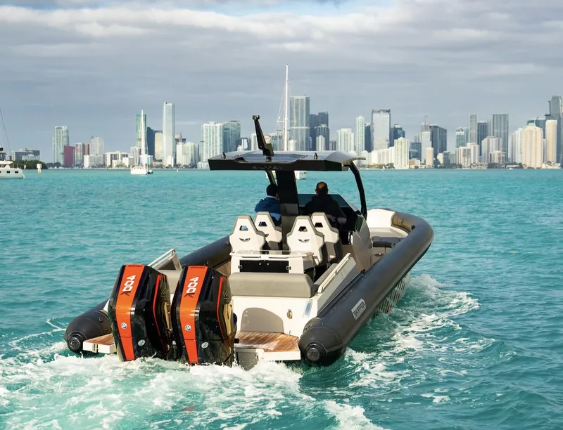 Slide: The Image of Skipper-BSK 38 boat cruising in turquoise waters with city skyline in background, 2024 model. - 4