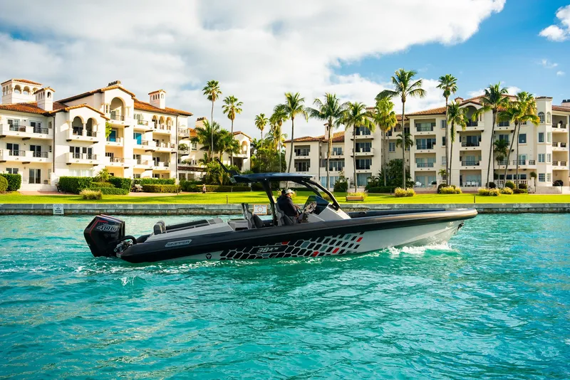 Slide: The Image of 2024 Skipper-BSK 38 boat cruising in turquoise waters near luxury waterfront apartments. - 25