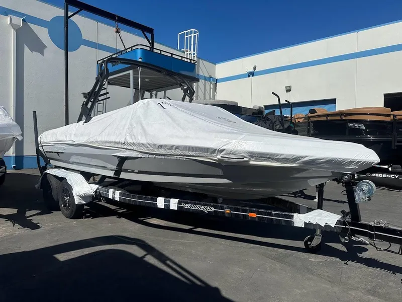 Slide: The Image of 2024 Sanger V215 S boat covered on a trailer in a dealership lot. - 1