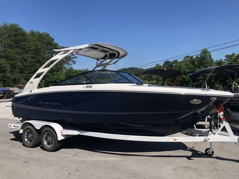 The Image of 2025 Regal LS2 Ultimate boat on trailer, parked outdoors under clear blue sky. - 1