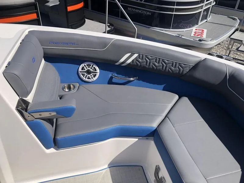 Slide: The Image of 2025 Regal LS2 Ultimate boat interior with gray and blue seating, cup holder, and speaker. - 5