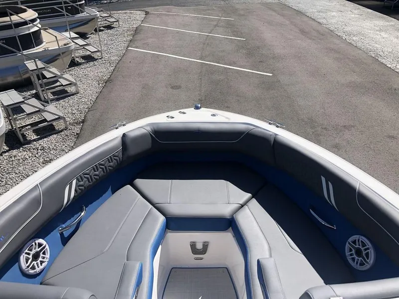 Slide: The Image of 2025 Regal LS2 Ultimate boat interior with gray and blue seating, parked on asphalt. - 9