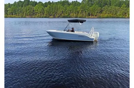 Slide: The Image of 2023 Stingray 172SC boat cruising on a serene lake with forested shoreline. - 5