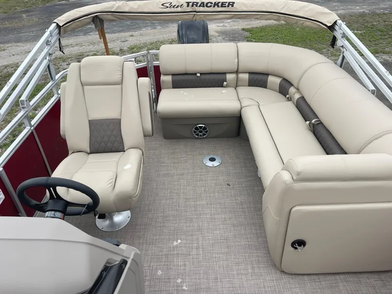 Slide: The Image of 2024 Sun Tracker Party Barge 20 DLX interior with beige seating and steering console. - 3