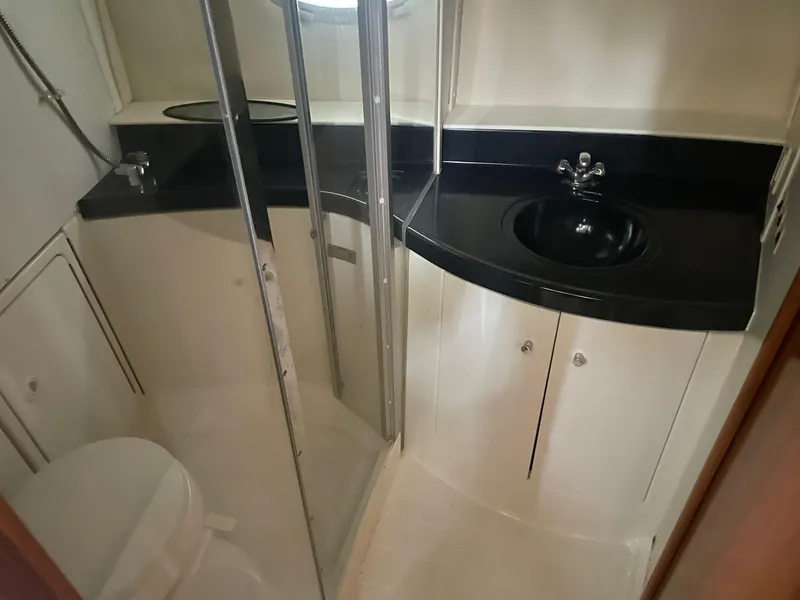 Slide: The Image of 2002 Carver 346 Motor Yacht bathroom with black countertop, sink, and shower. - 17