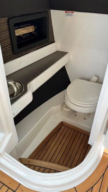 Slide: The Image of 2022 Sea Ray SLX 280 boat bathroom with toilet, sink, and wooden floor. - 8