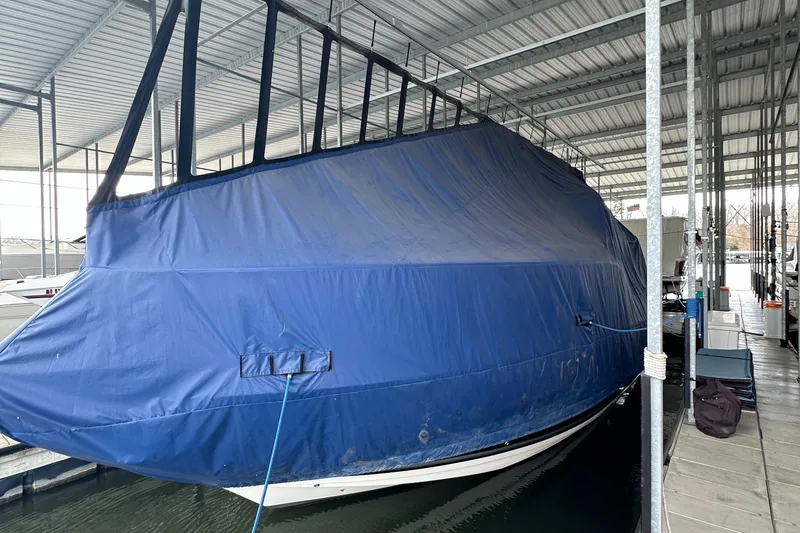 Slide: The Image of 2006 Rinker 360 Express Cruiser covered in blue tarp, docked in a sheltered marina. - 17