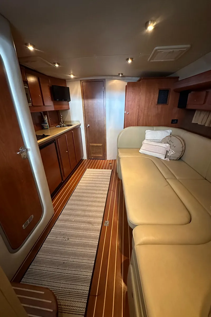 Slide: The Image of Interior of a 2006 Rinker 360 Express Cruiser with wood cabinetry and beige seating. - 19