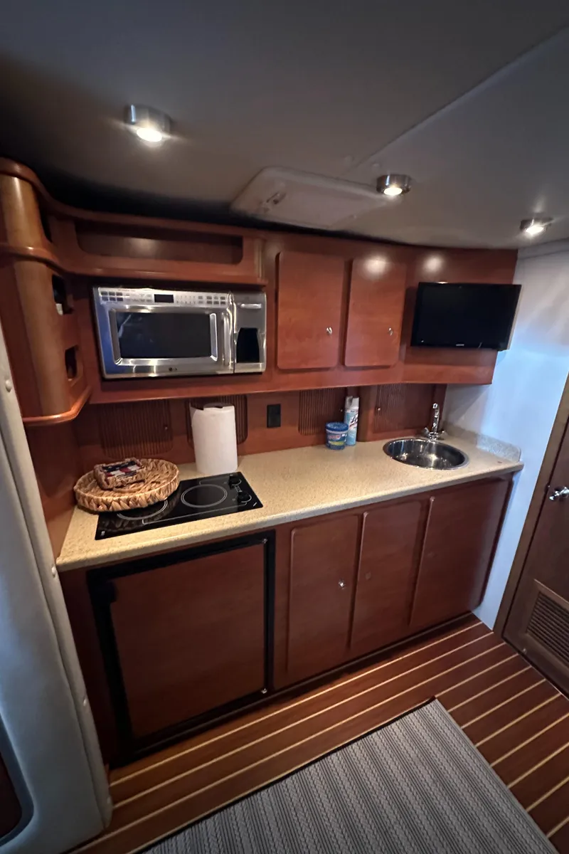 Slide: The Image of 2006 Rinker 360 Express Cruiser kitchen with microwave, sink, and stove. - 24