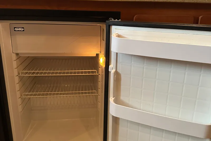 Slide: The Image of Open refrigerator inside a 2006 Rinker 360 Express Cruiser boat. - 25