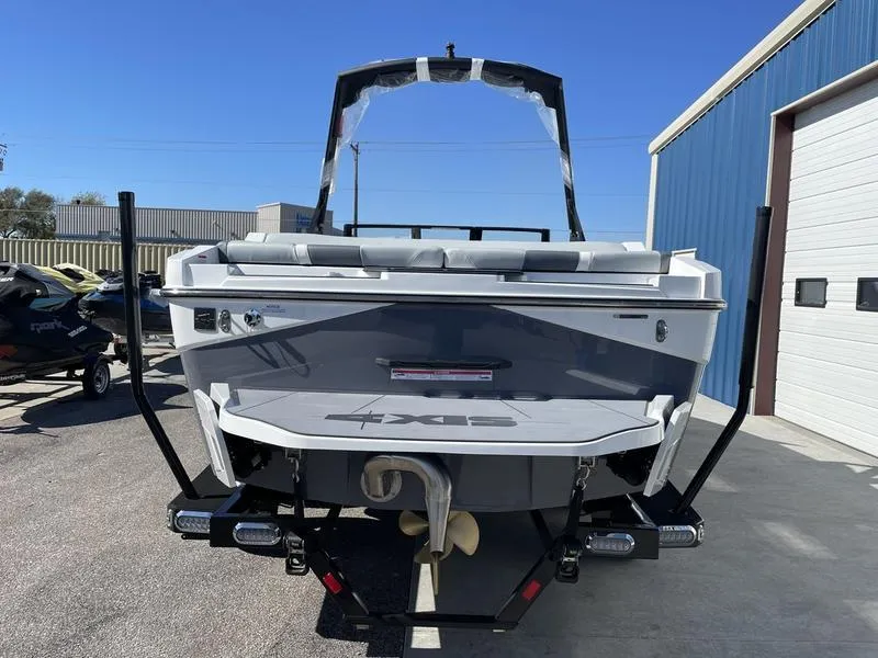 Slide: The Image of 2024 Axis T220-r boat on trailer, rear view, parked outside a blue building. - 5