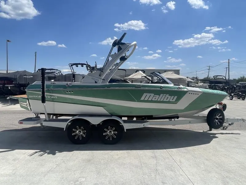 Slide: The Image of 2024 Malibu 21 LX boat on trailer under clear sky. - 2