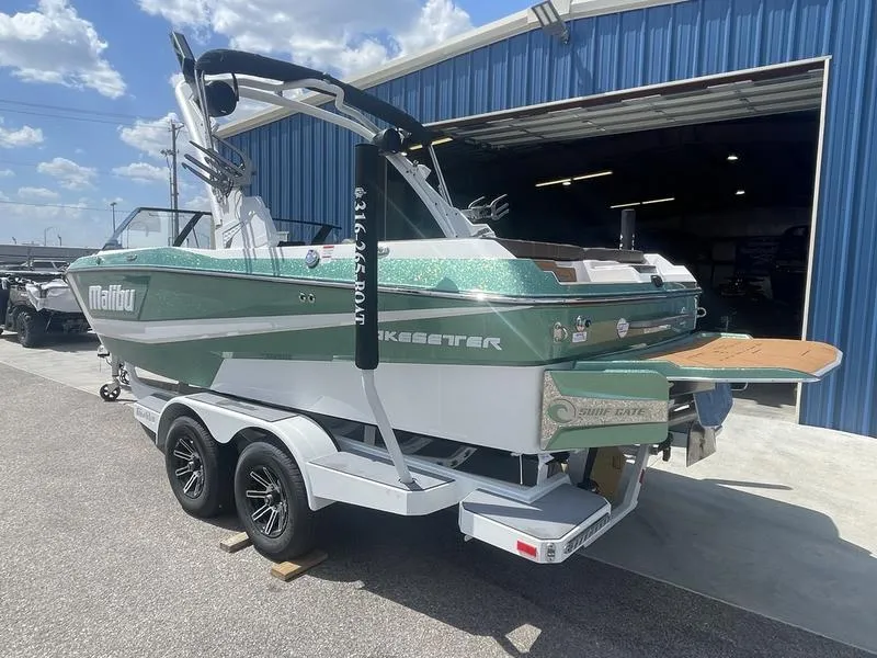 Slide: The Image of 2024 Malibu 21 LX boat on a trailer outside a blue warehouse. - 4