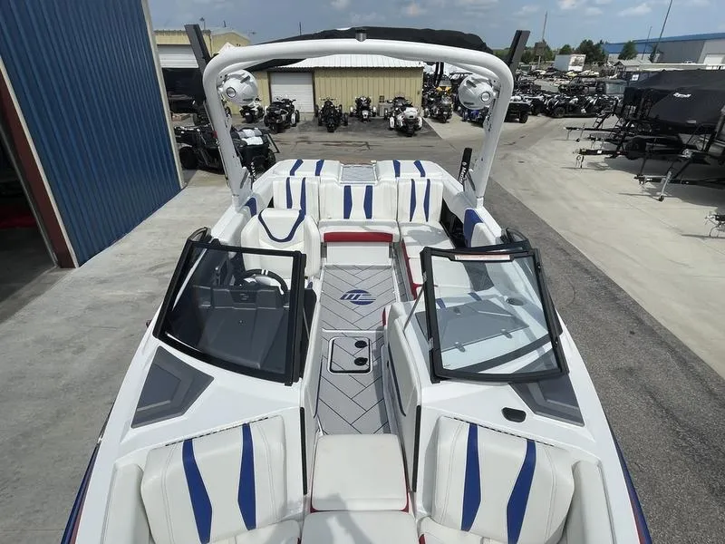 Slide: The Image of 2024 Malibu 22 LSV boat with white and blue interior, docked at a marina. - 17