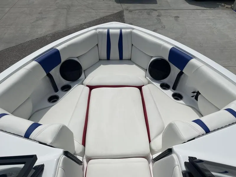 Slide: The Image of 2024 Malibu 22 LSV boat interior with white and blue seating, cup holders, and speakers. - 24