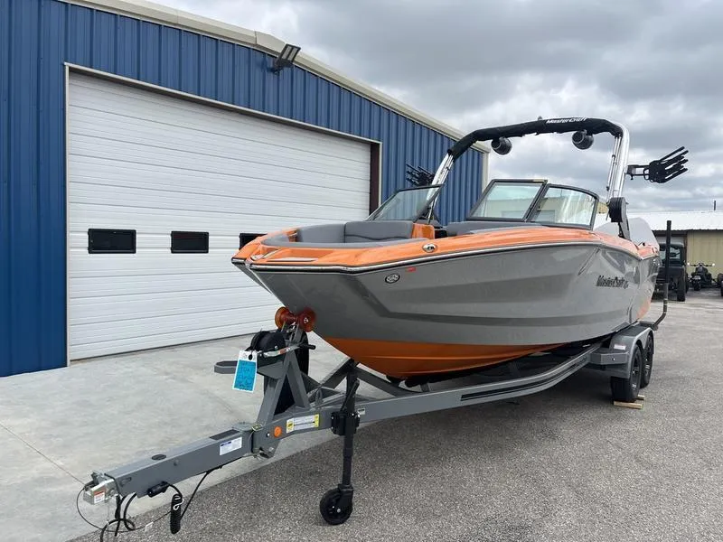 Slide: The Image of 2024 MasterCraft NXT23 boat on trailer outside blue warehouse. - 3