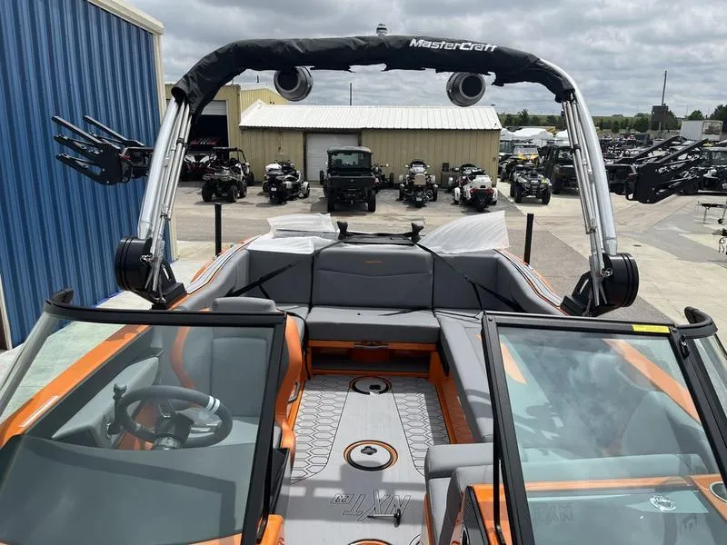 Slide: The Image of 2024 MasterCraft NXT23 boat with orange and gray interior, docked at a marina. - 6