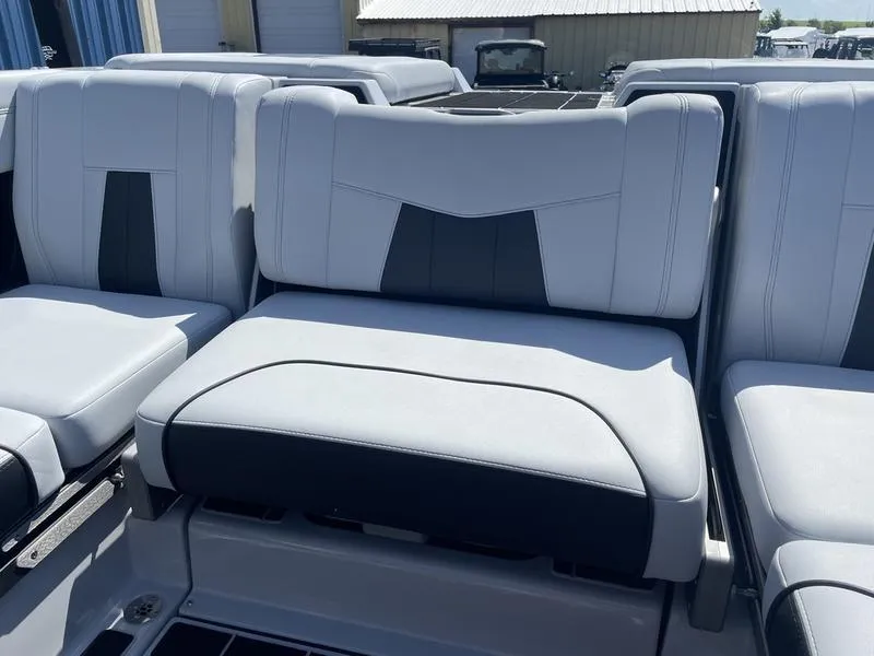 Slide: The Image of 2023 Malibu 24 MXZ boat interior seating with white and black upholstery. - 12