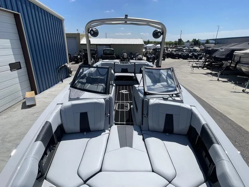 Slide: The Image of 2023 Malibu 24 MXZ boat with spacious seating and modern design at a marina. - 14