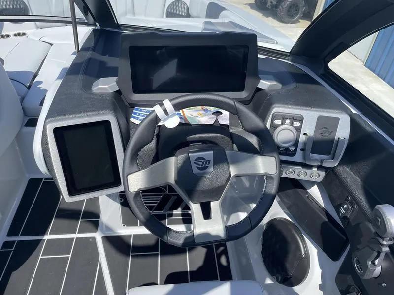 Slide: The Image of 2023 Malibu 24 MXZ boat dashboard with steering wheel and digital displays. - 22