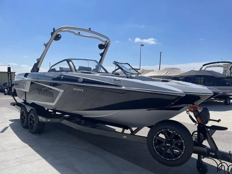 Slide: The Image of 2023 Malibu 24 MXZ boat on a trailer in a marina. - 3