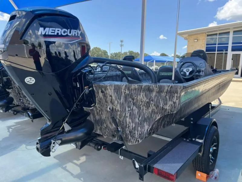 Slide: The Image of 2024 Havoc Boats 1756 FRRSC with Mercury engine, camo design, parked outdoors. - 3