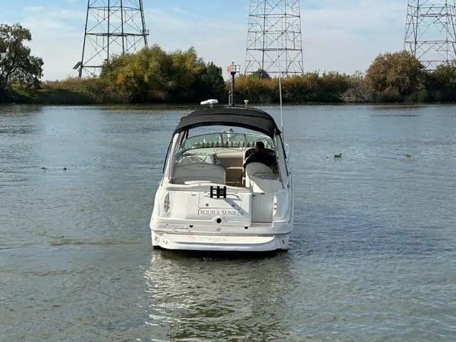 Slide: The Image of 2003 Sea Ray 280 Sundancer boat on calm water with trees and power lines in the background. - 14