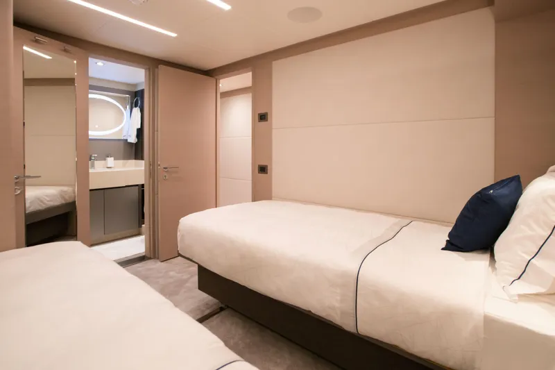 Slide: The Image of Luxurious bedroom interior in 2025 Nomad 95 SUV yacht, featuring twin beds and ensuite bathroom. - 12