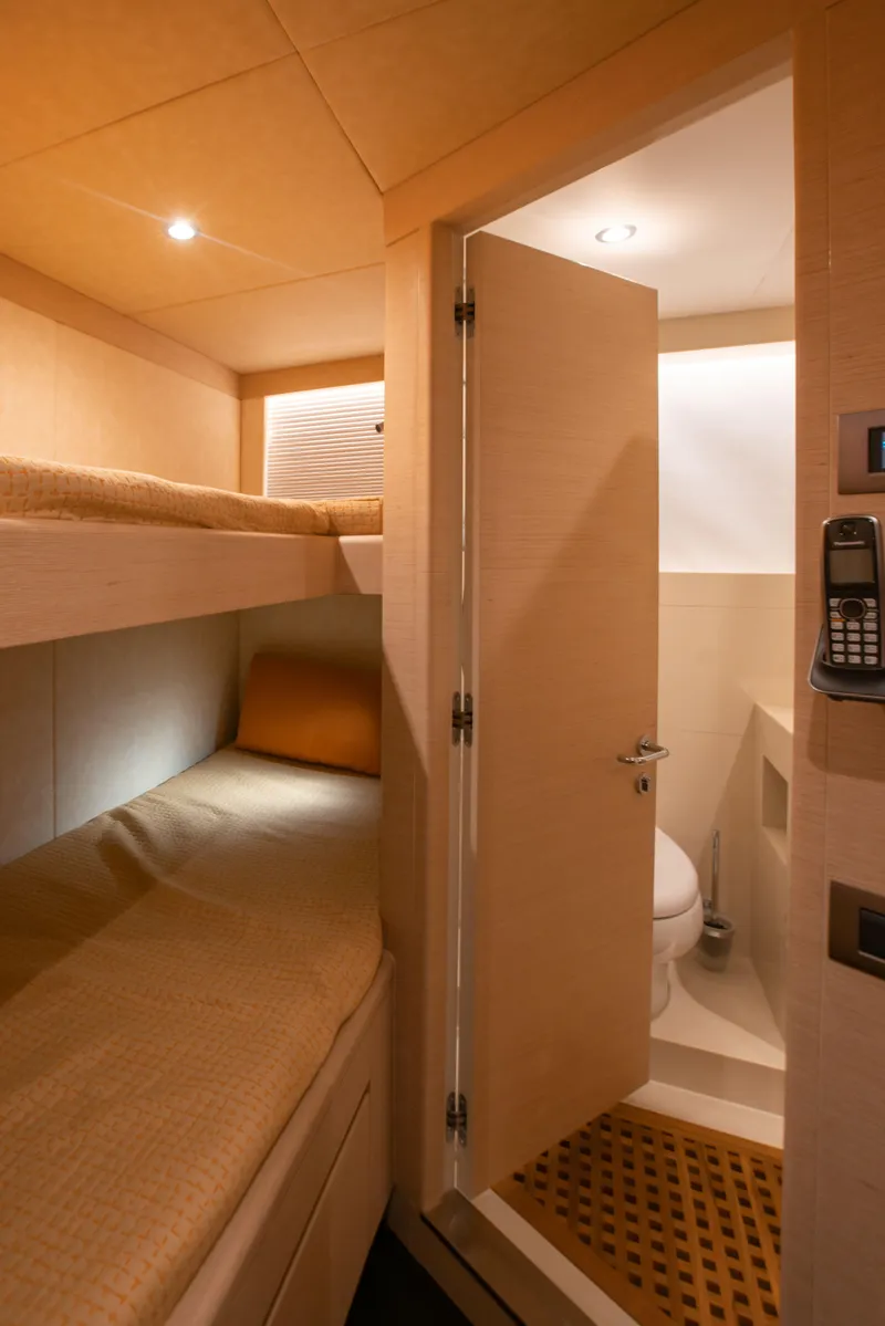 Slide: The Image of Interior of 2025 Nomad 95 SUV yacht with cozy bunk bed and compact bathroom. - 14