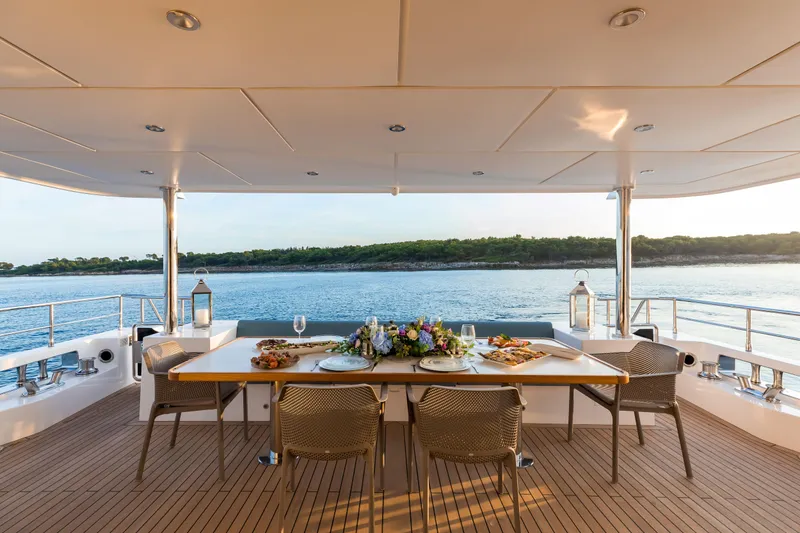 Slide: The Image of Luxury dining setup on 2025 Nomad 95 SUV yacht, overlooking serene waters. - 19
