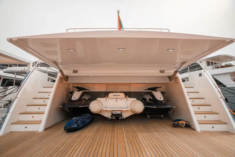 Slide: The Image of Luxurious 2025 Nomad 95 SUV yacht with open garage, showcasing jet skis and watercraft. - 24