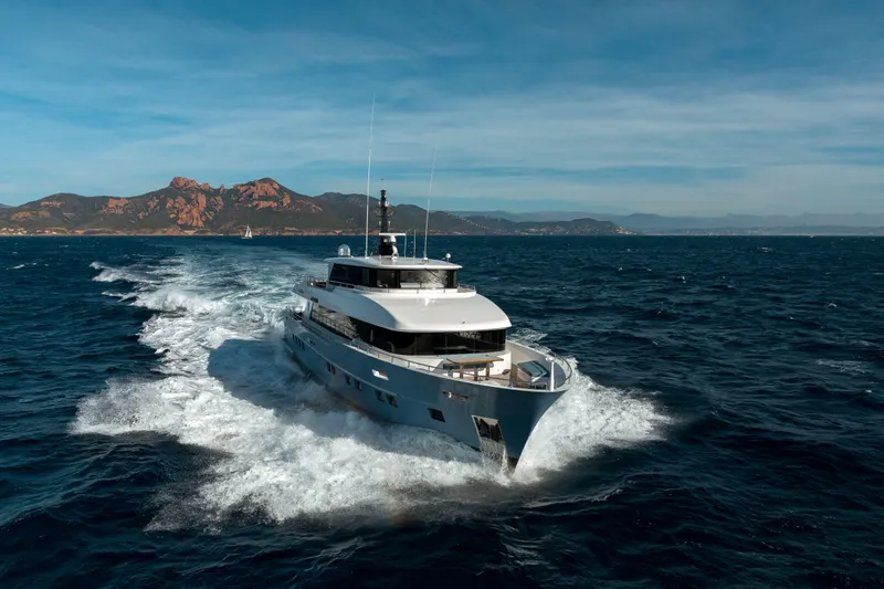 Slide: The Image of 2025 Nomad 95 SUV yacht cruising on open sea with scenic mountain backdrop. - 38