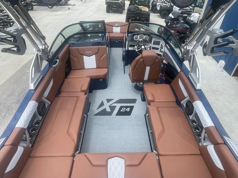 Slide: The Image of 2023 MasterCraft XT24 boat interior with brown leather seating and modern dashboard. - 16