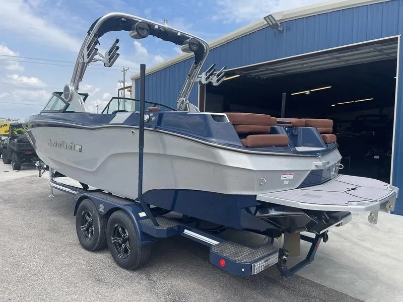 Slide: The Image of 2023 MasterCraft XT24 boat on trailer outside blue warehouse. - 4