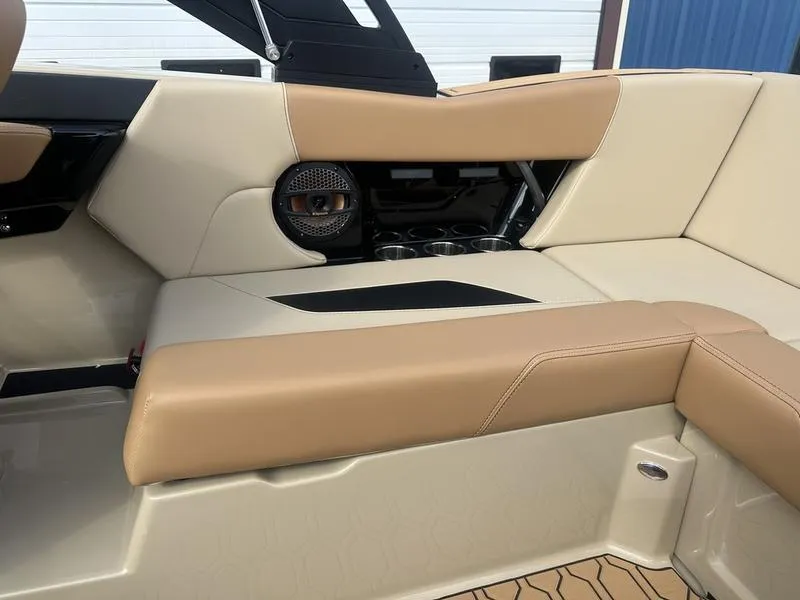 Slide: The Image of 2024 MasterCraft NXT21 boat interior with beige and tan seating, speaker, and cup holders. - 13