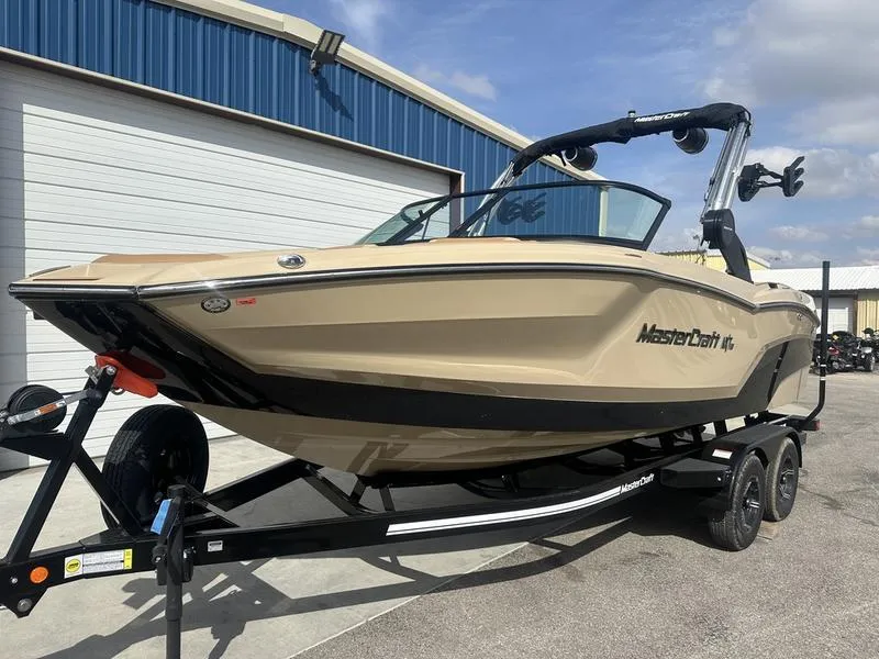 Slide: The Image of 2024 MasterCraft NXT21 boat on trailer outside blue warehouse. - 3