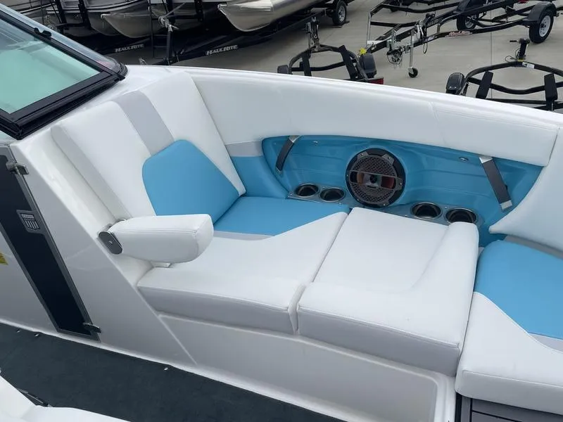 Slide: The Image of 2019 MasterCraft X26 boat interior with white and blue seating, cup holders, and speaker. - 23