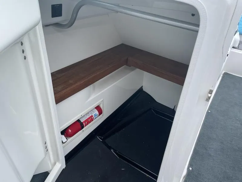 Slide: The Image of 2019 MasterCraft X26 boat interior storage compartment with wooden bench and fire extinguisher. - 25