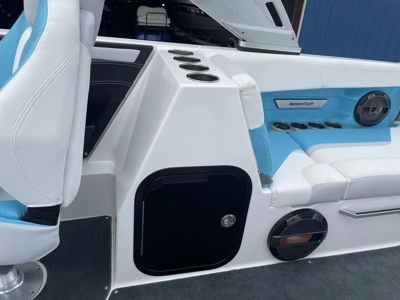 Slide: The Image of 2019 MasterCraft X26 boat interior with white and blue seating, cup holders, and storage compartments. - 27