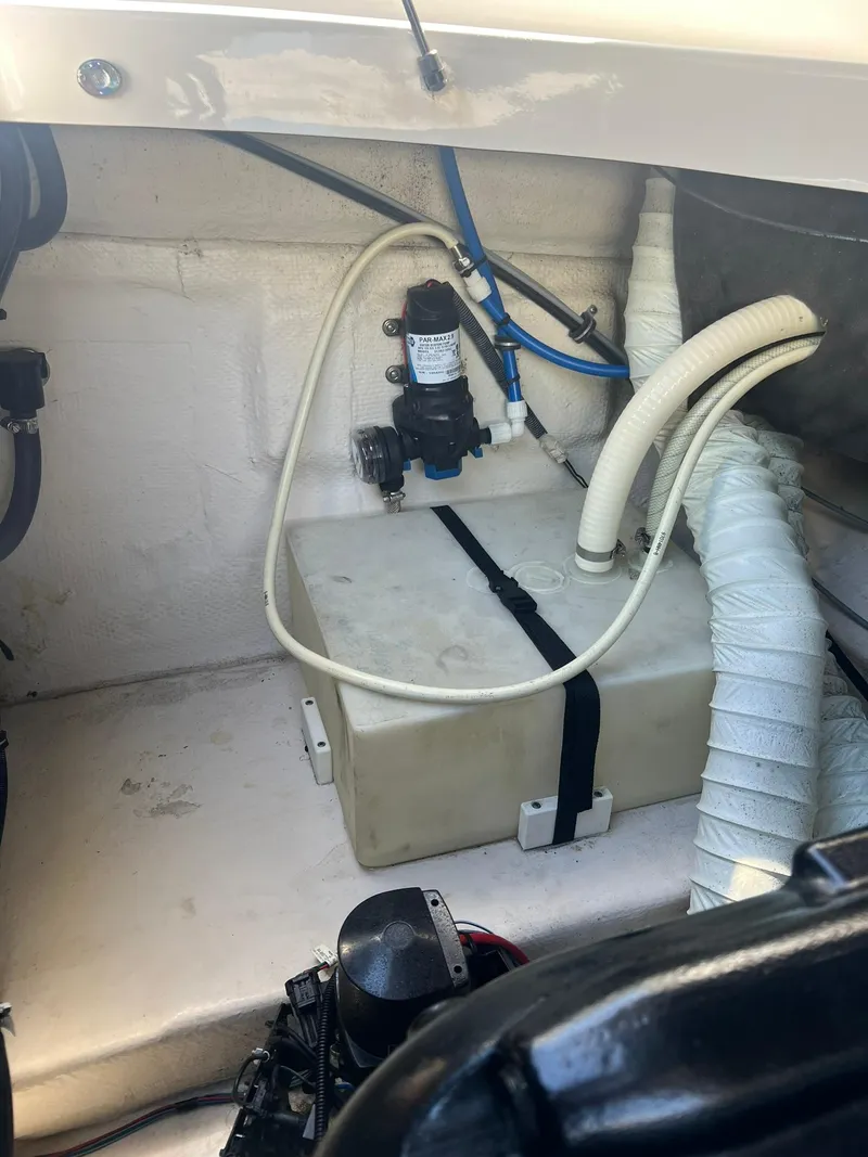 Slide: The Image of 2014 Rinker 246 Captiva Bowrider engine compartment with water pump and hoses. - 19